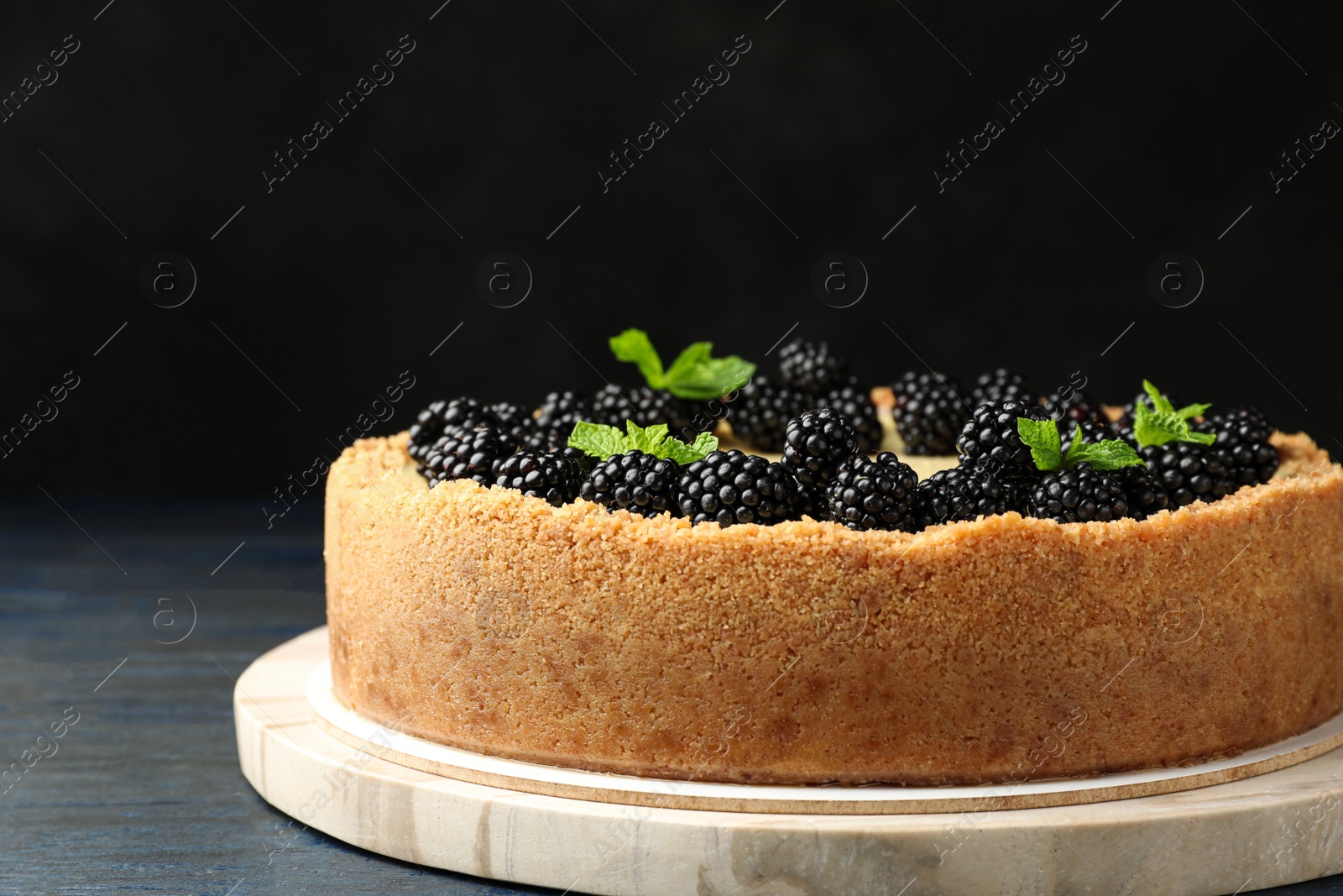 Photo of Delicious cheesecake decorated with blackberries on table