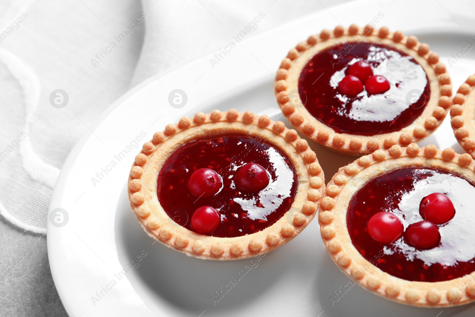 Photo of Tasty tartlets with jam on plate, closeup