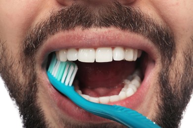 Man brushing teeth on white background, closeup. Dental care