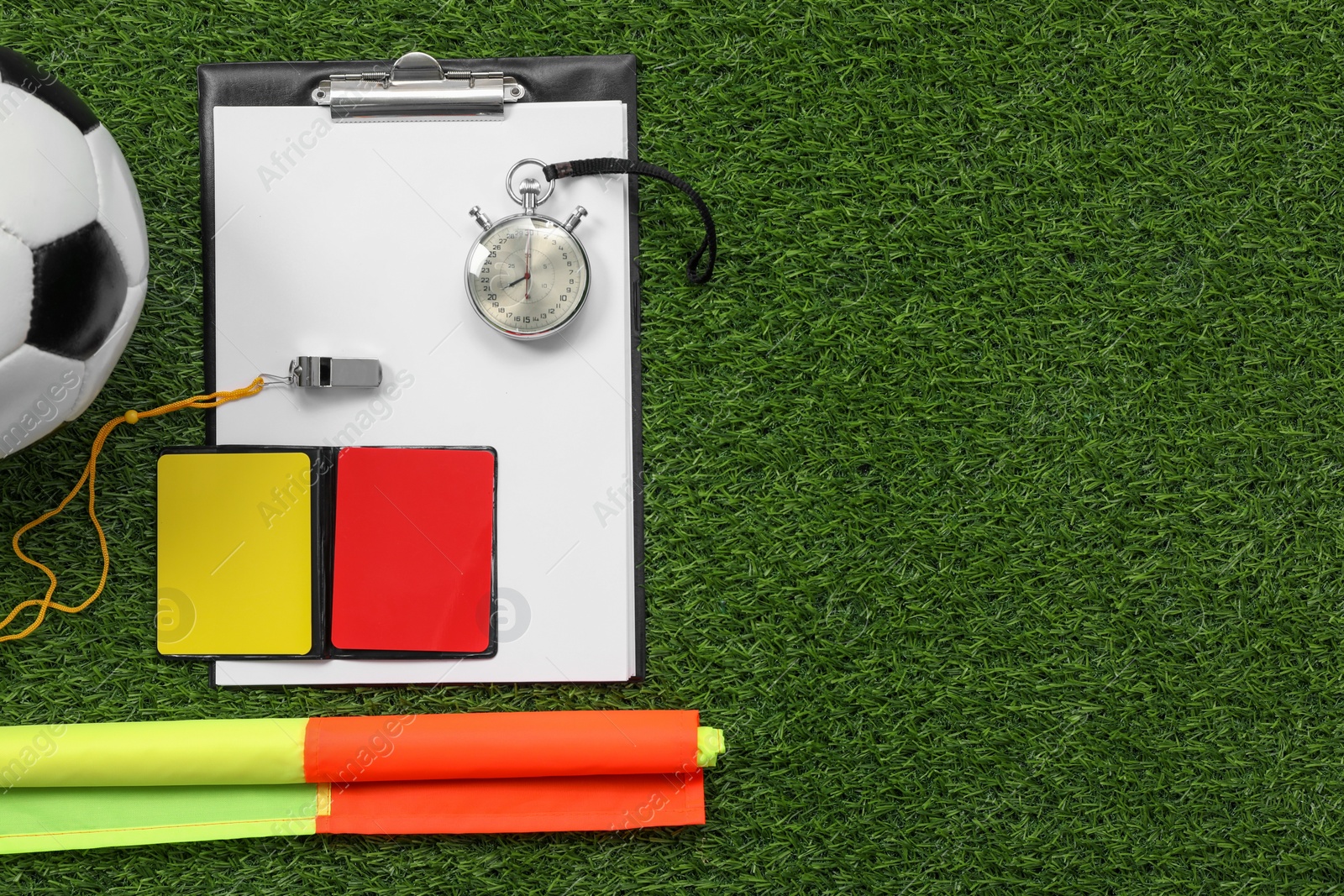 Photo of Soccer ball and different referee equipment on green grass, flat lay. Space for text