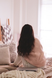 Woman relaxing at home, back view. Cozy atmosphere