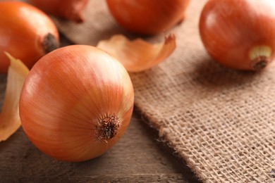 Photo of Many ripe onions on wooden table, closeup