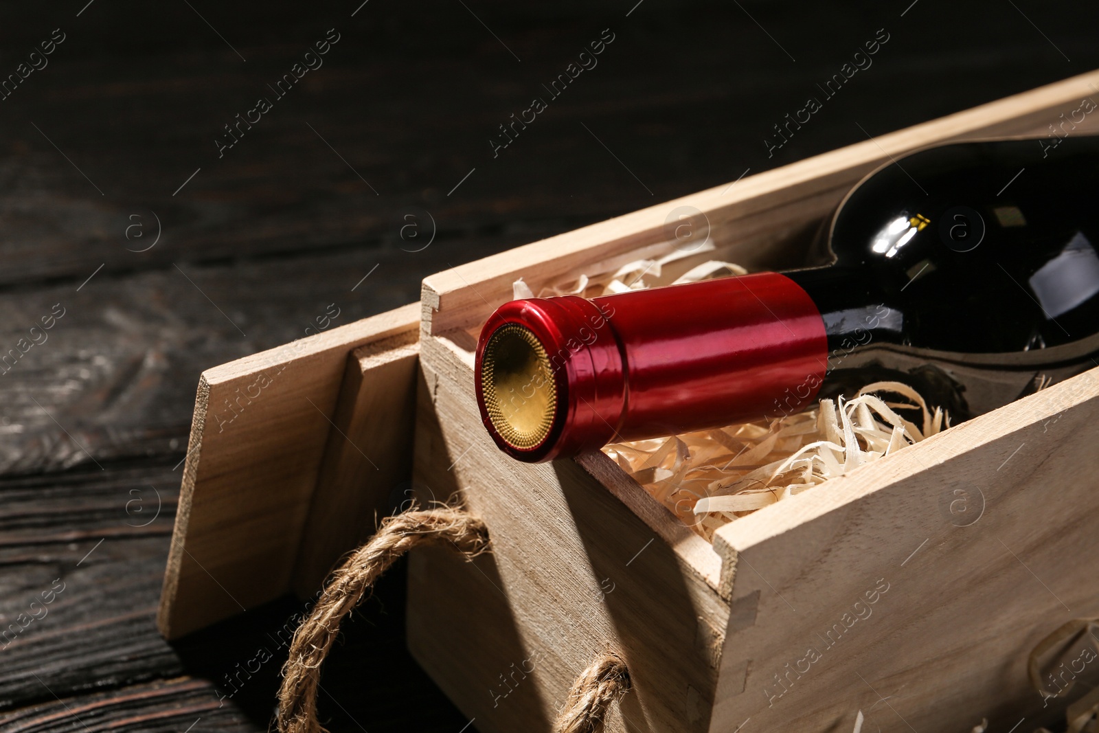 Photo of Crate with bottle of wine on wooden table, closeup