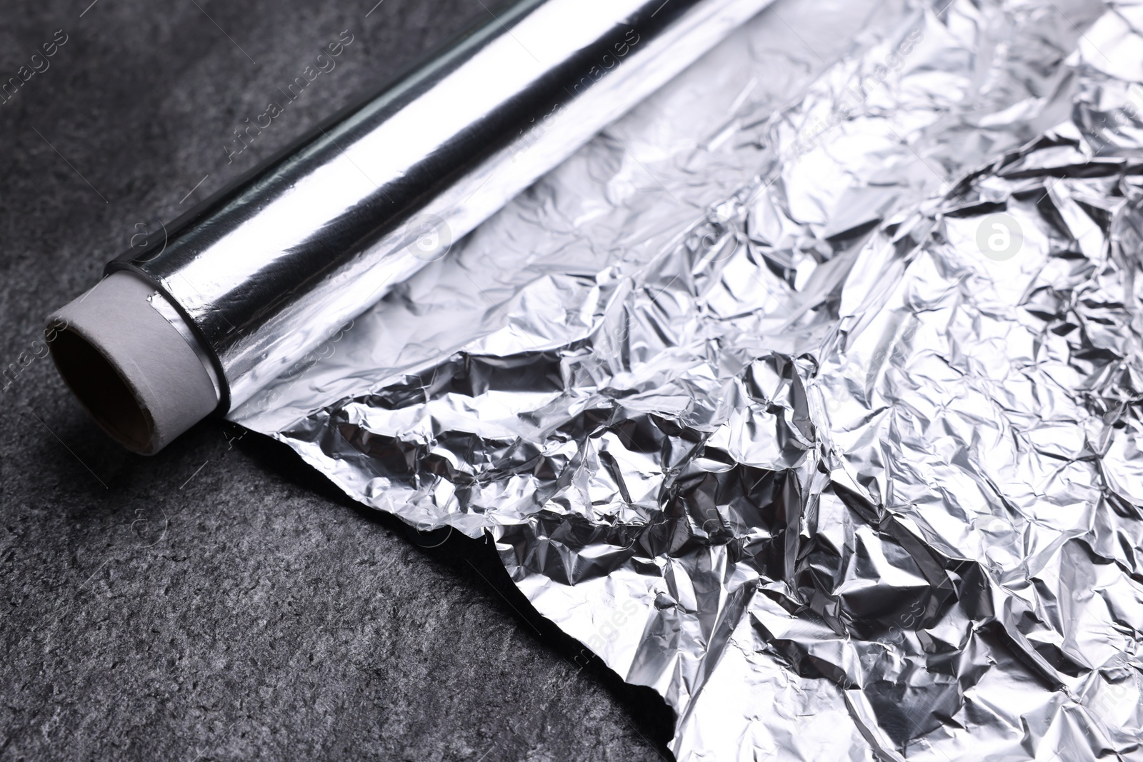 Photo of Roll of aluminum foil on grey table, closeup