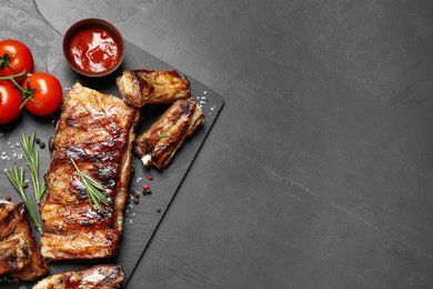 Photo of Delicious grilled ribs on black table, flat lay. Space for text
