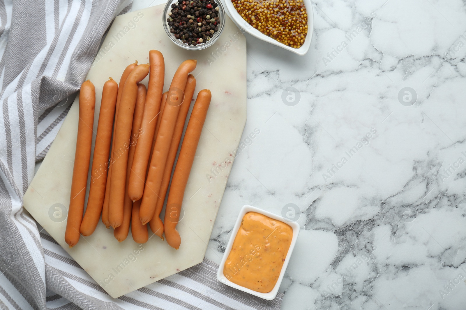 Photo of Fresh delicious sausages, mustard, and pepper on white marble table, flat lay. Space for text