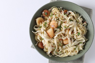 Photo of Delicious scallop pasta with spices in bowl on white table, top view. Space for text