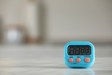 Photo of Kitchen timer on white marble table against blurred background. Space for text