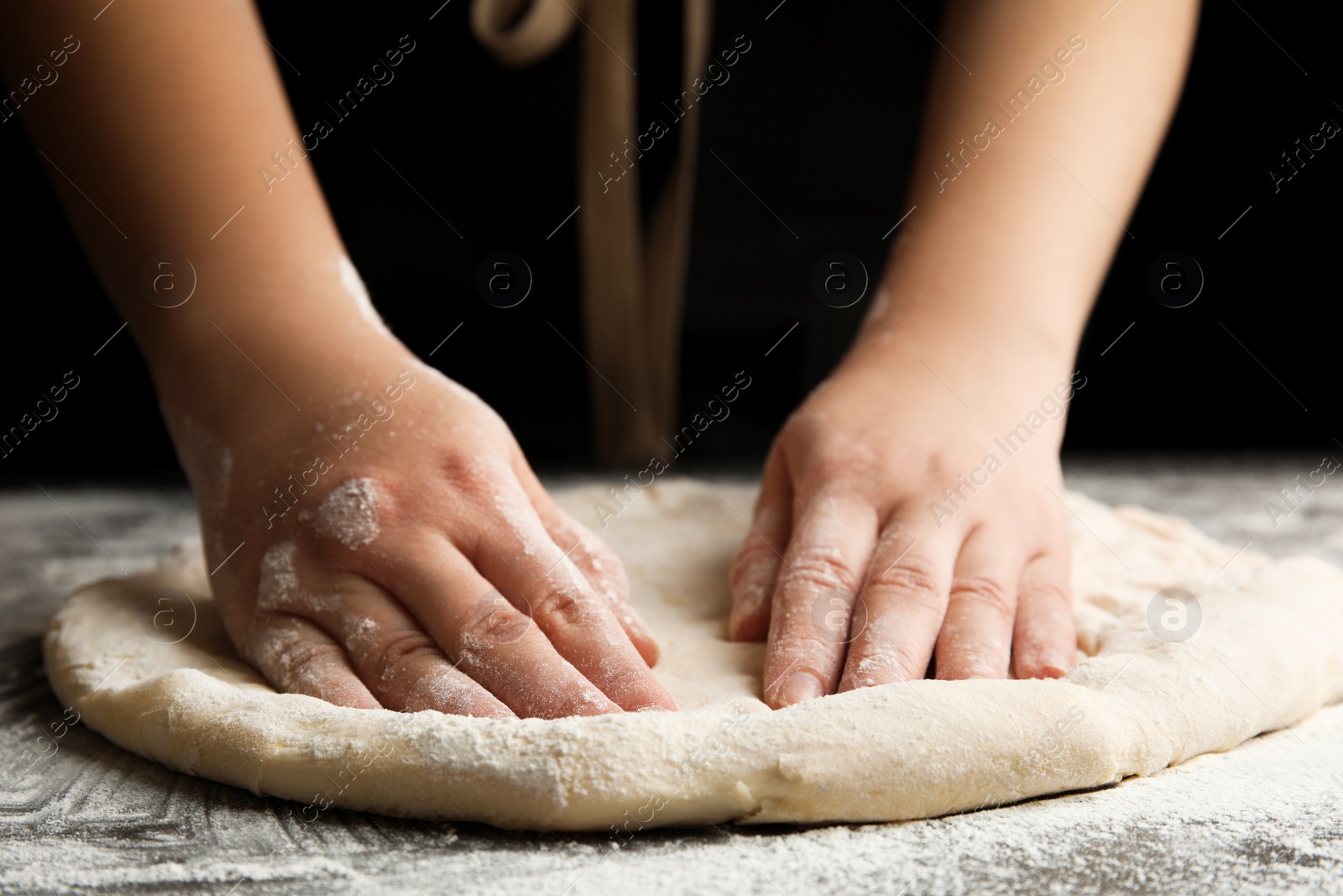 Photo of Woman kneading dough for pizza at grey table, closeup