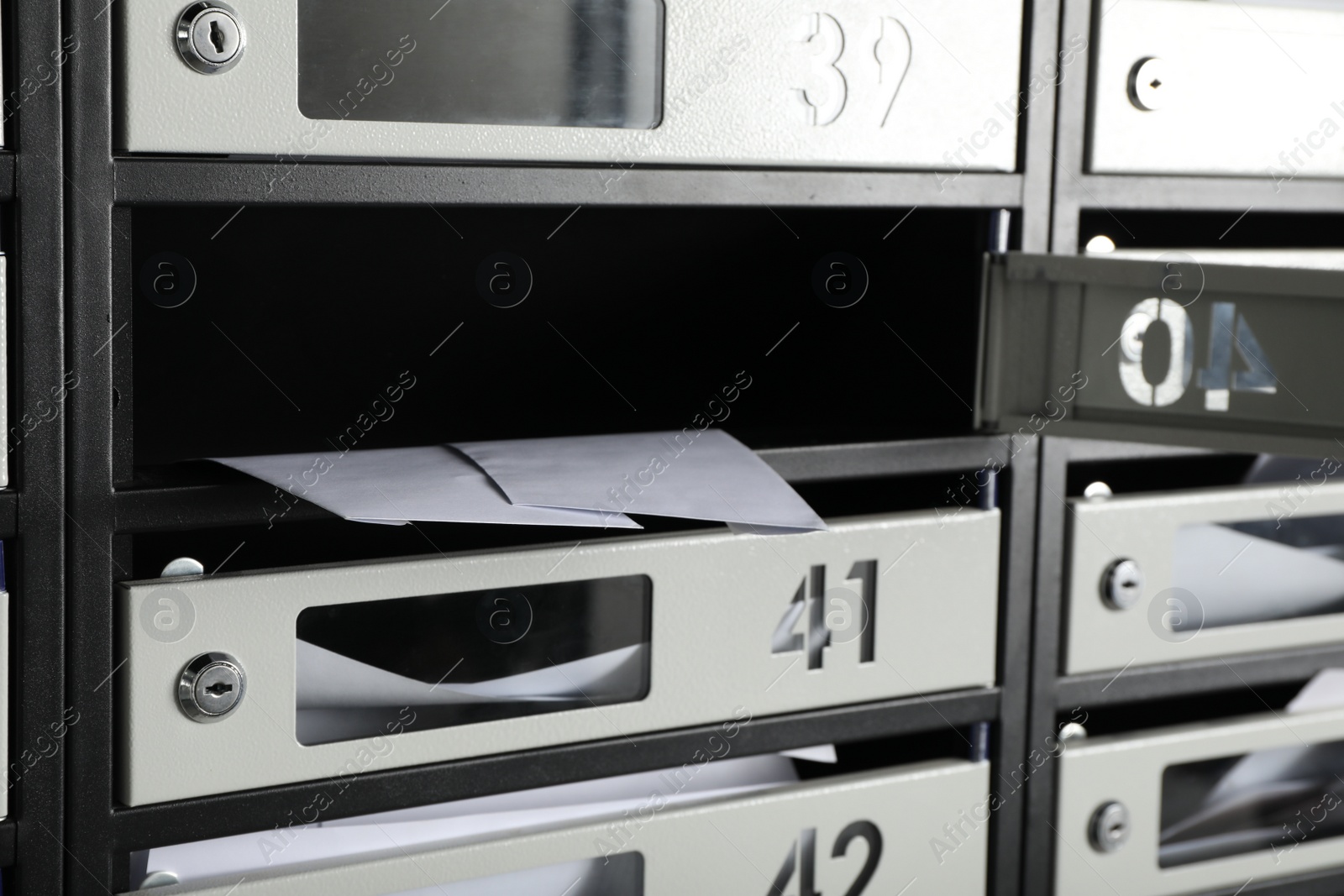 Photo of Open mailbox with keyhole, number and receipts, closeup