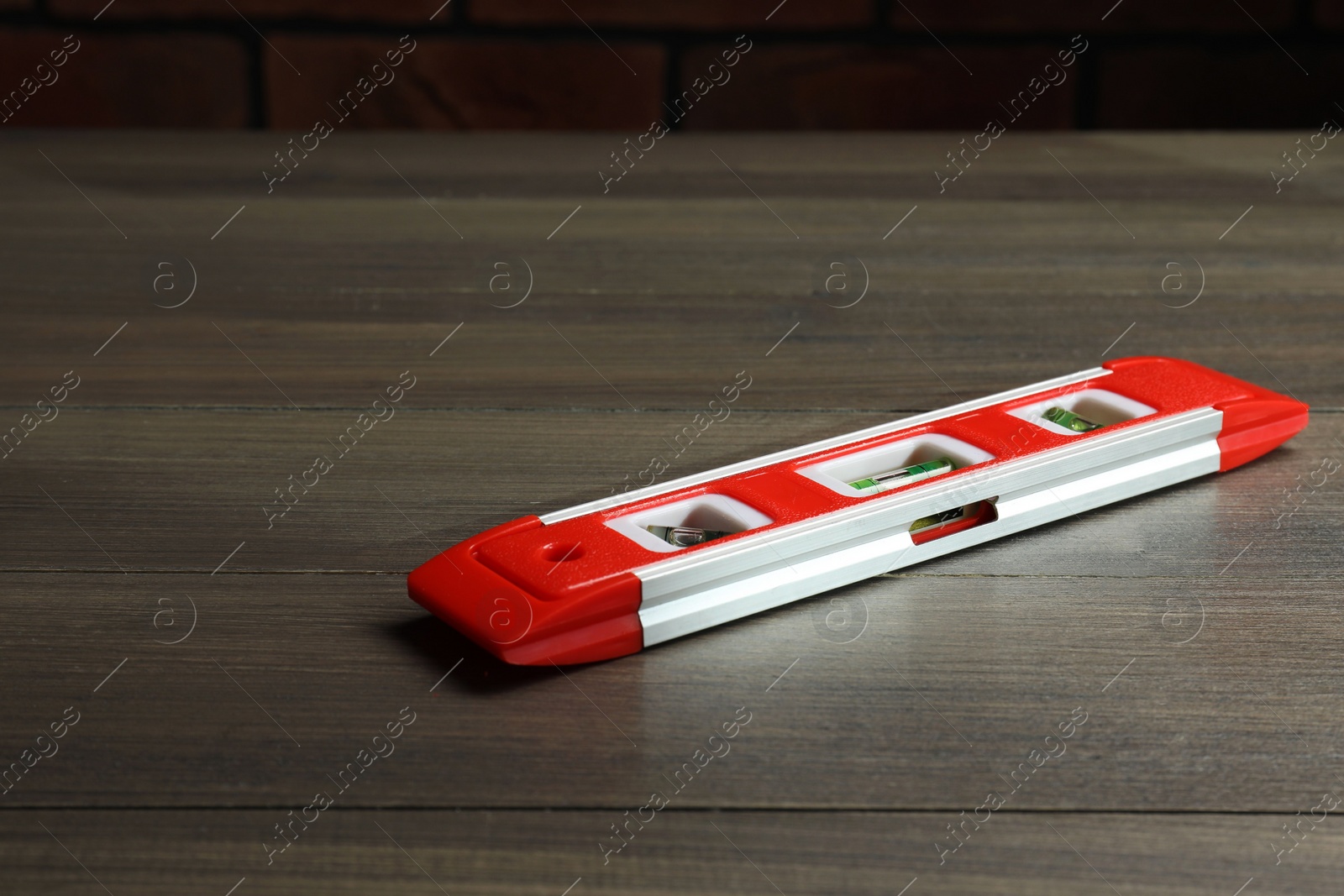 Photo of Red building level on wooden table. Construction tool