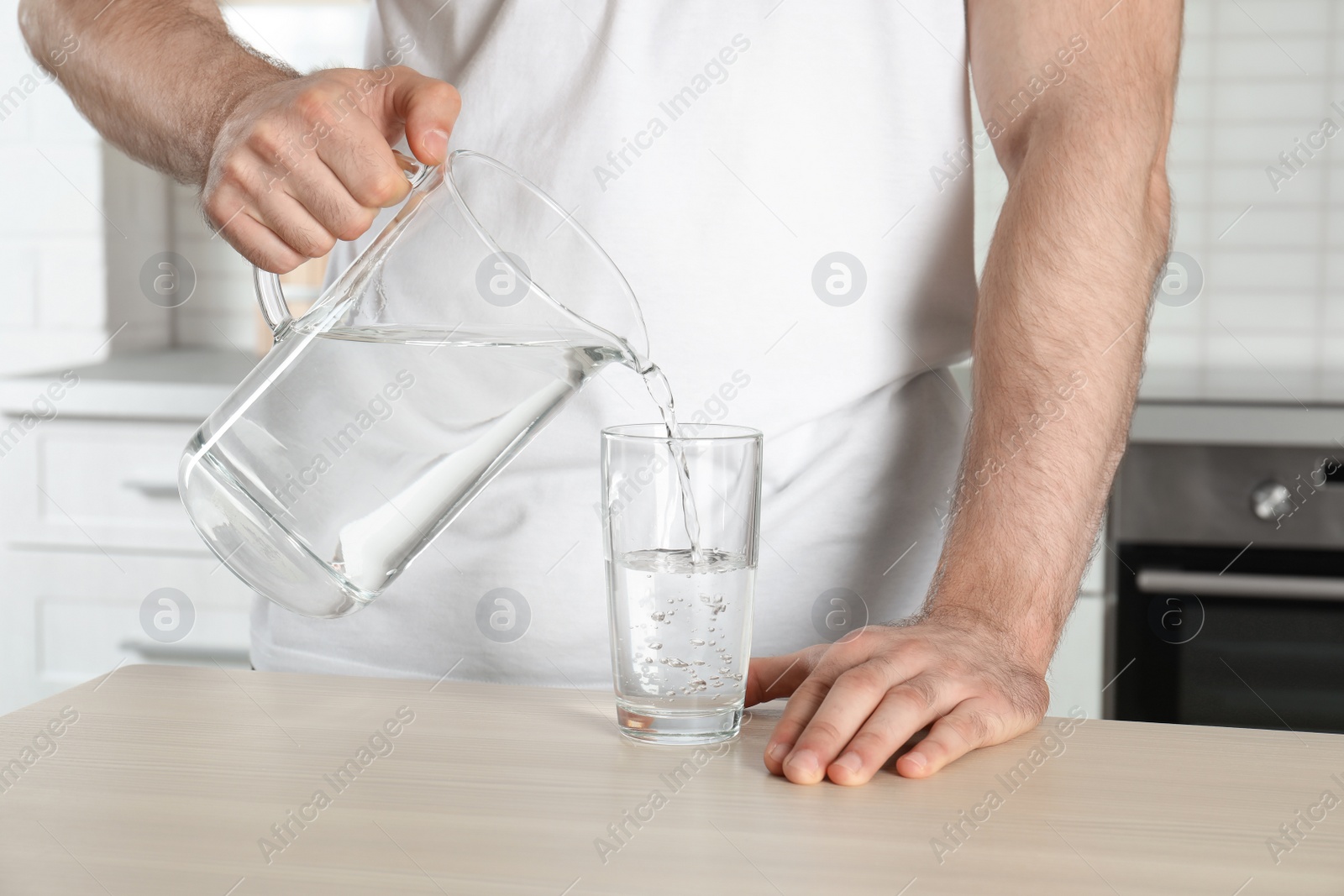 Photo of Man pouring water into glass at table, closeup