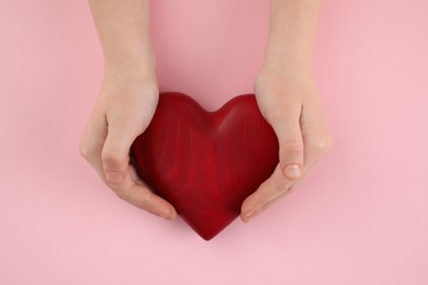 Photo of Woman holding red heart on pink background, top view