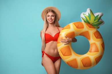 Pretty young woman wearing stylish bikini with inflatable ring on blue background
