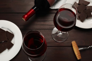 Photo of Tasty red wine and chocolate on wooden table, above view