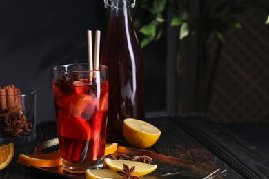 Photo of Glass of aromatic punch drink and ingredients on table, space for text