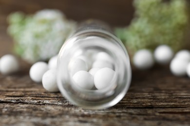 Bottle with homeopathic remedy on wooden table, closeup