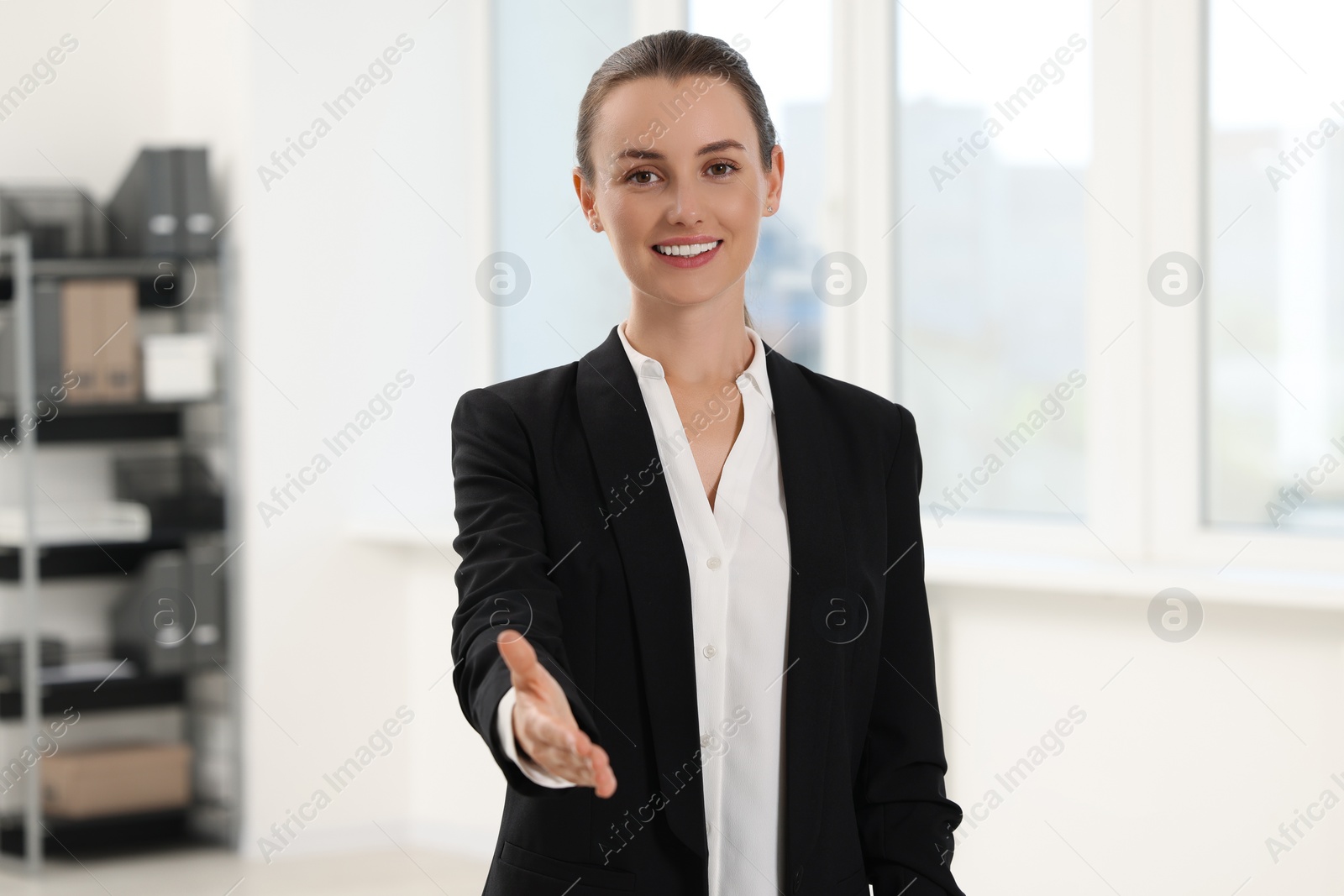 Photo of Happy woman welcoming and offering handshake in office