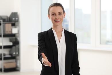 Photo of Happy woman welcoming and offering handshake in office