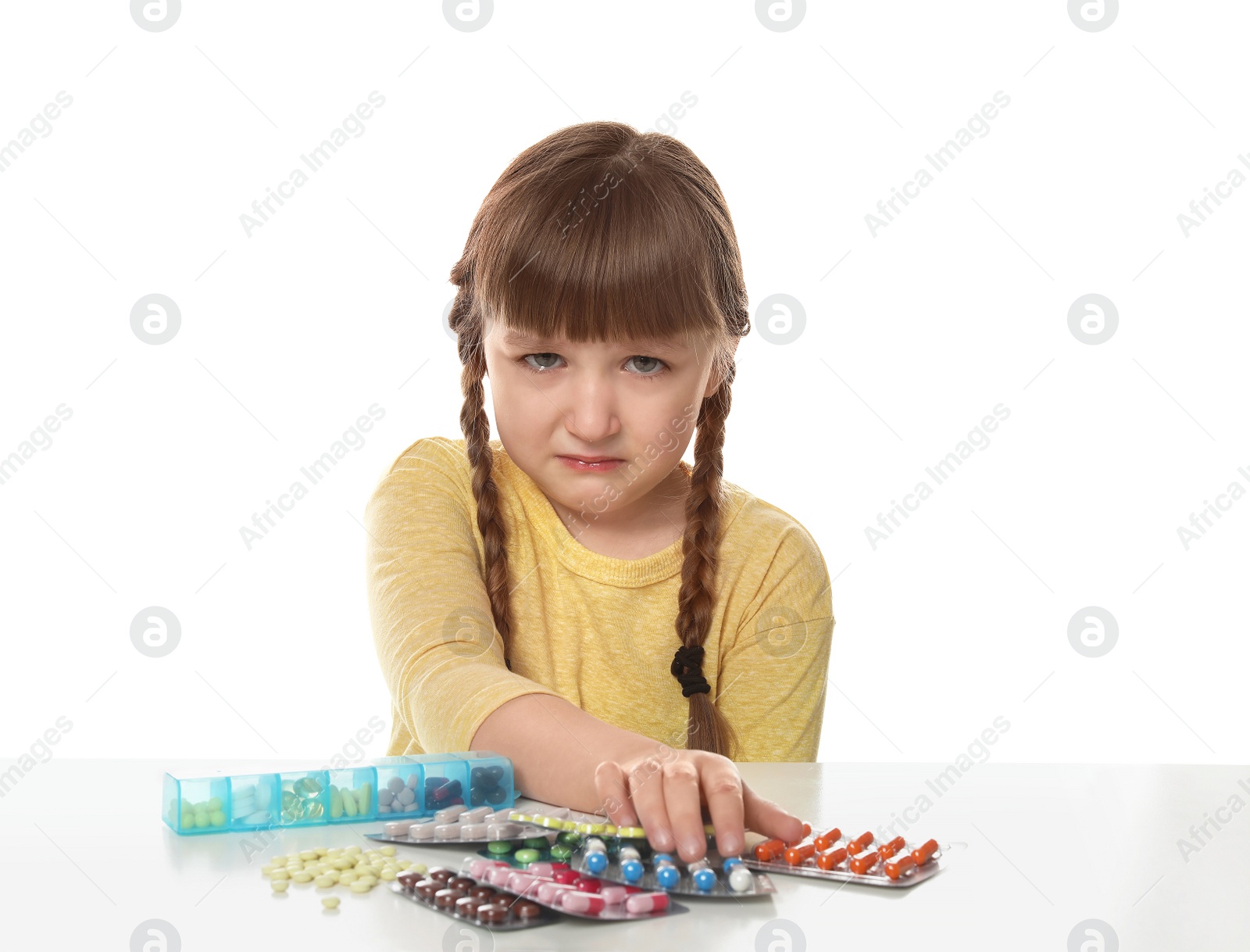 Photo of Crying little child with many different pills on white background. Danger of medicament intoxication