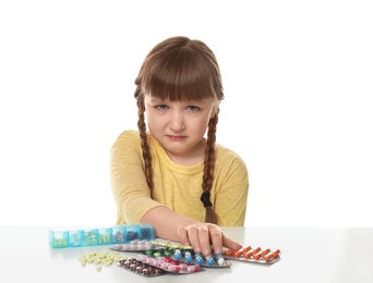 Crying little child with many different pills on white background. Danger of medicament intoxication