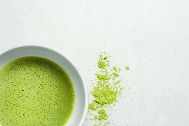 Cup of fresh matcha tea and green powder on light grey table, top view. Space for text