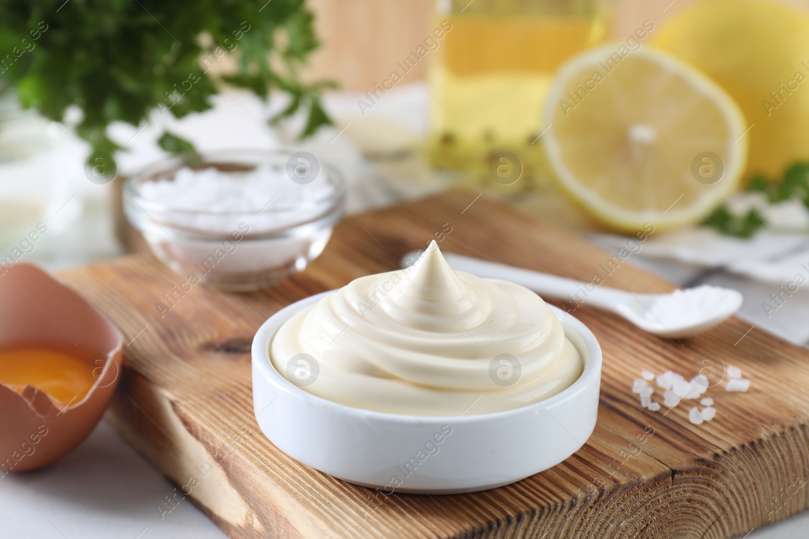 Photo of Fresh mayonnaise sauce in bowl and ingredients on table