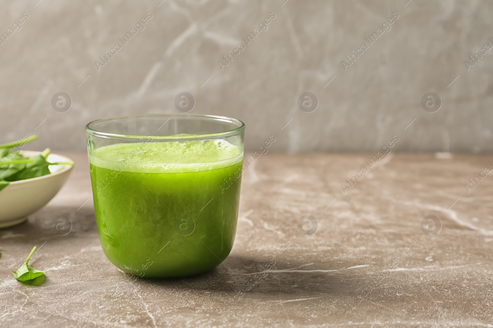 Photo of Glass with delicious detox juice and spinach on table