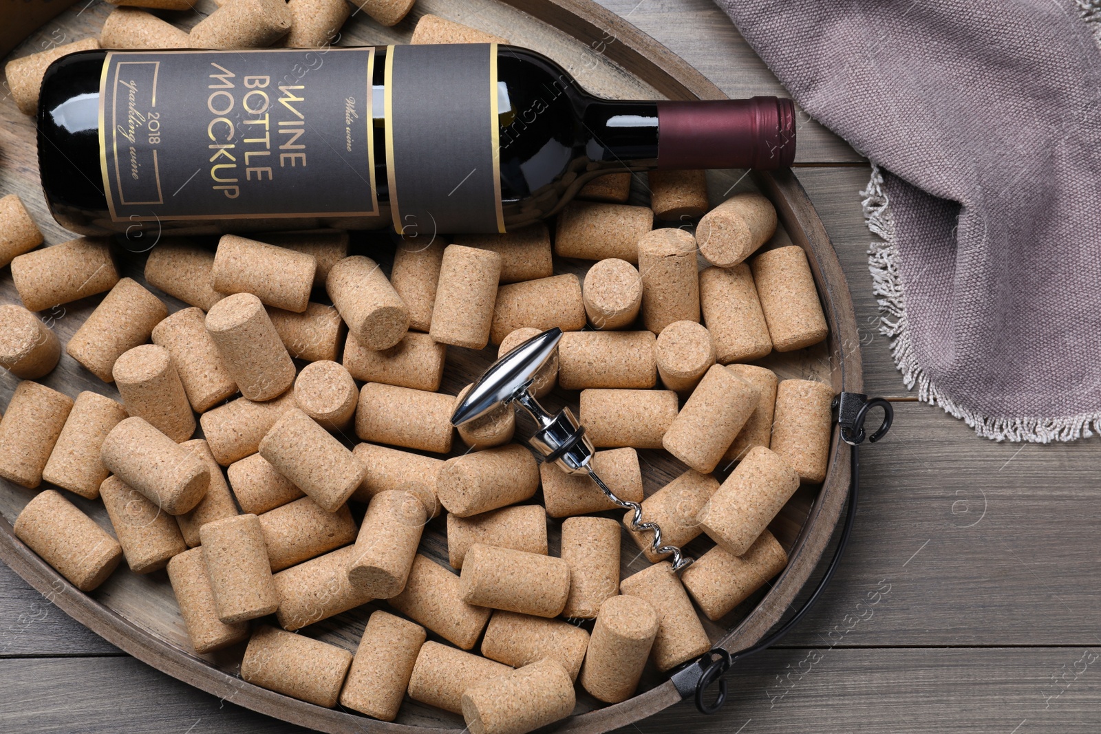 Photo of Tray with corkscrew, wine bottle and stoppers on wooden table, flat lay