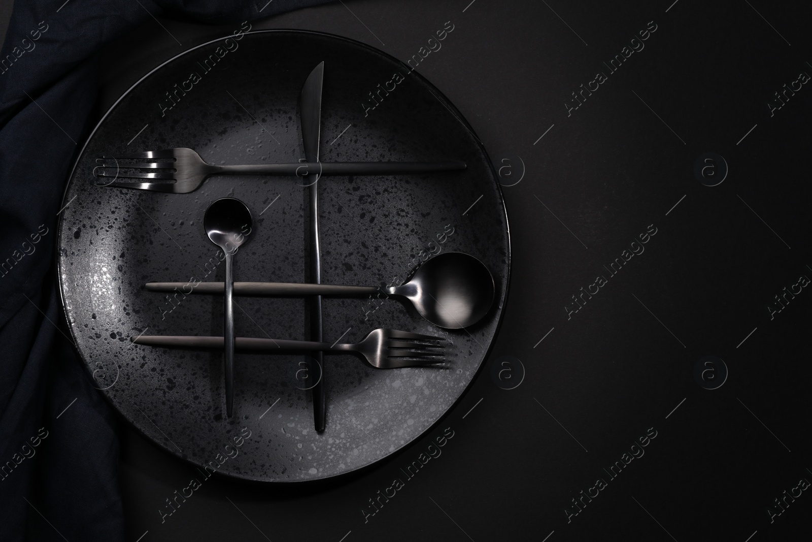 Photo of Stylish table setting. Plate, napkin and cutlery on black background, top view with space for text