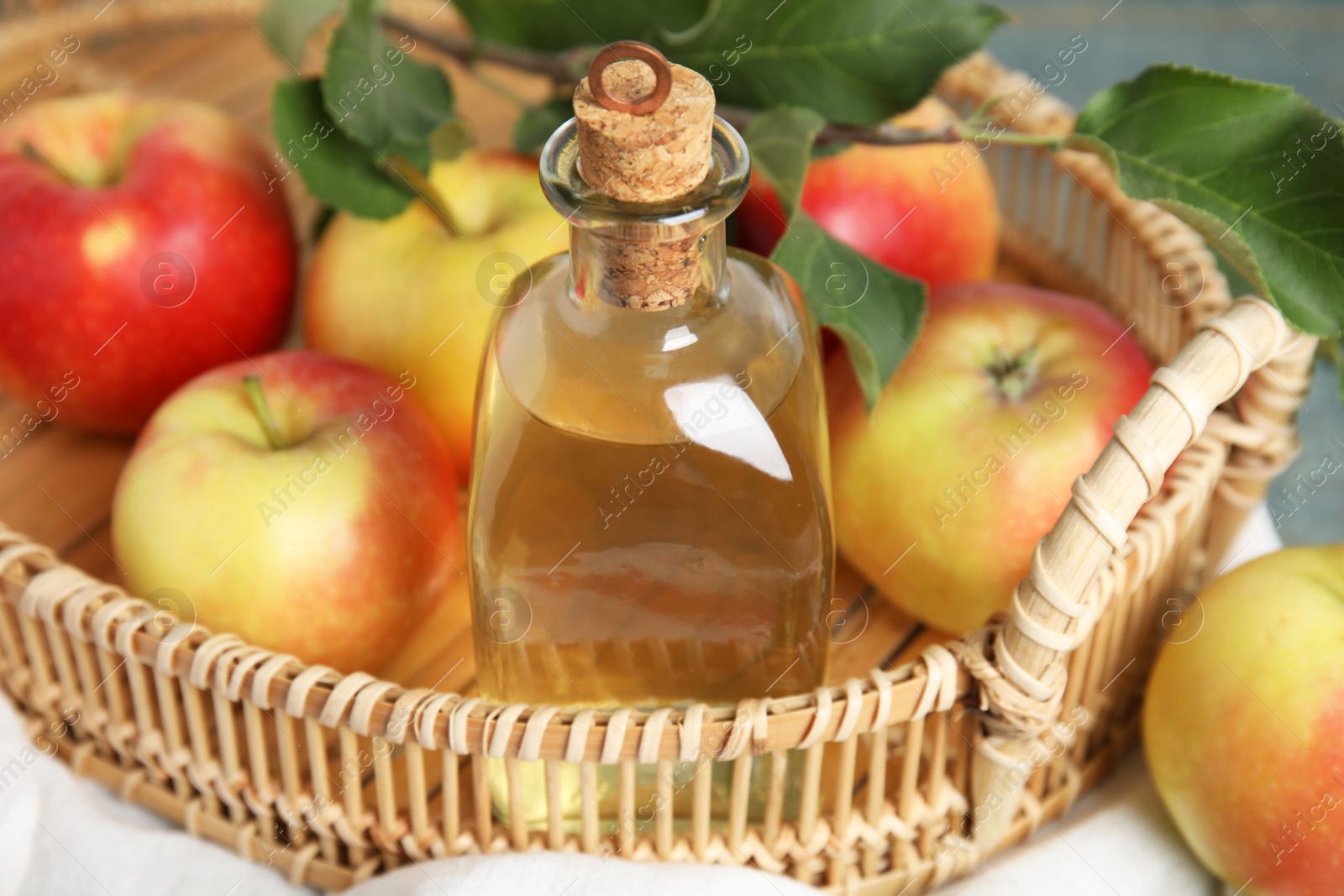 Photo of Natural apple vinegar and fresh fruits on tray, closeup