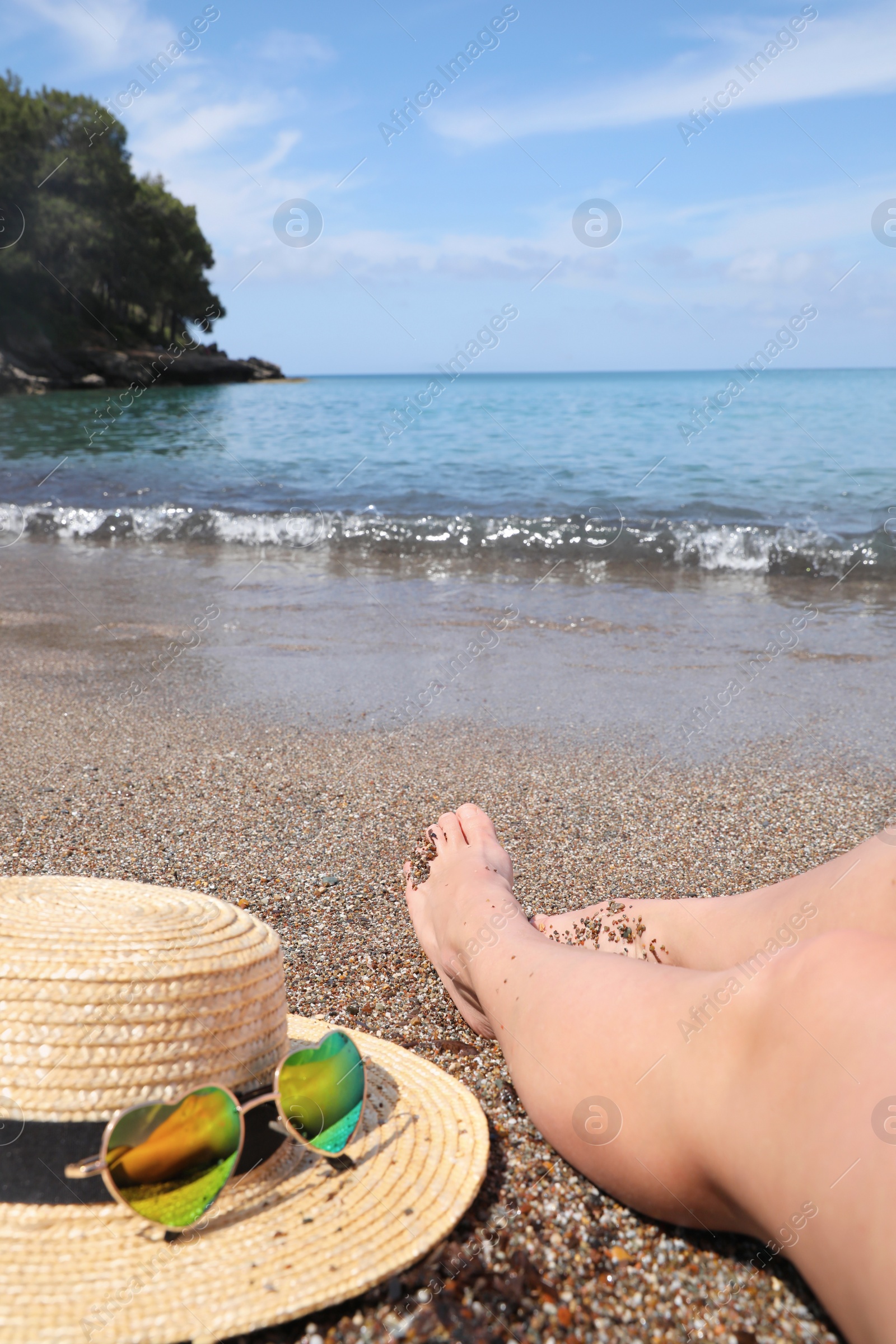 Photo of Woman with straw hat and heart shaped sunglasses on sea beach, closeup