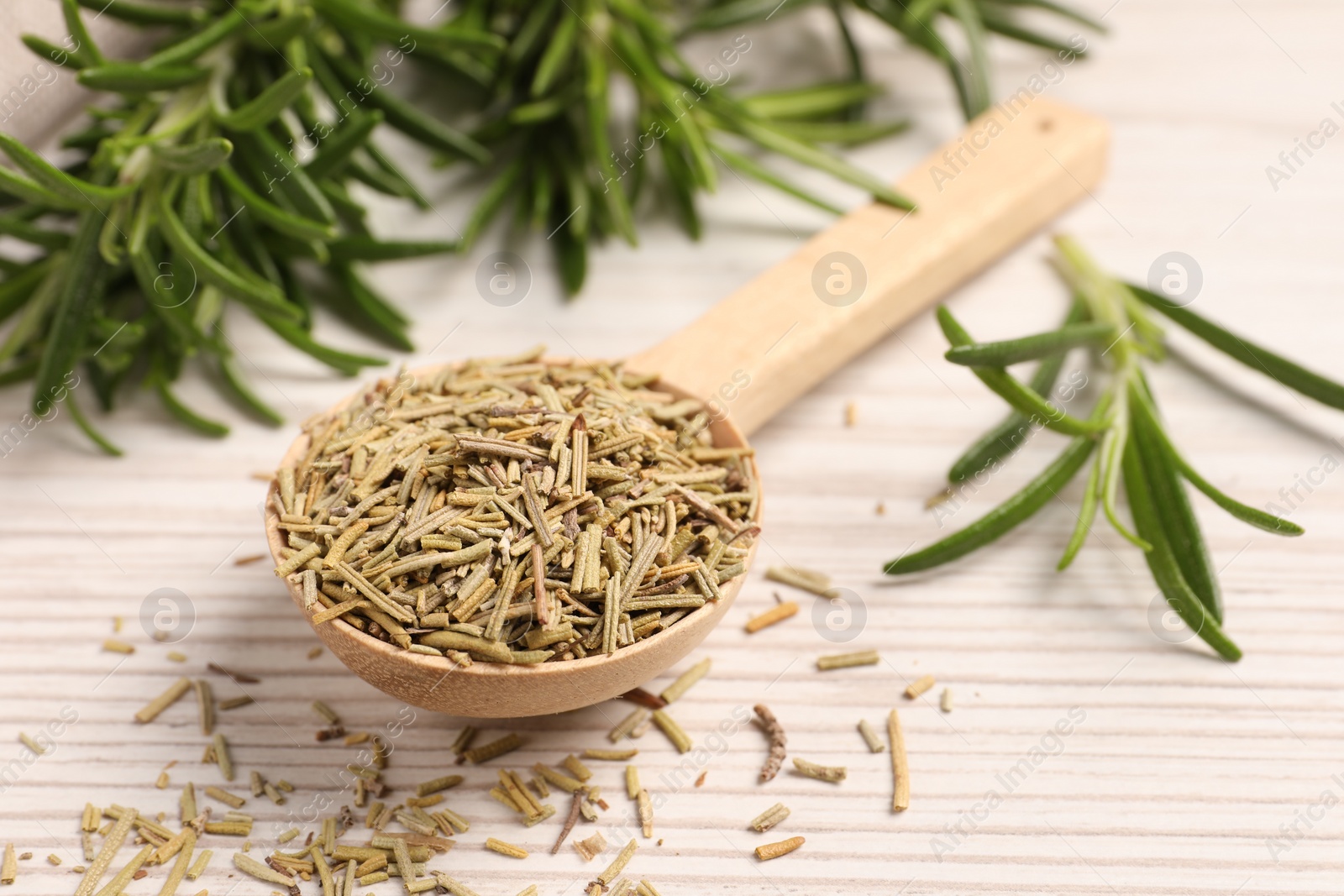 Photo of Spoon with dry rosemary and fresh twigs on white wooden table, closeup
