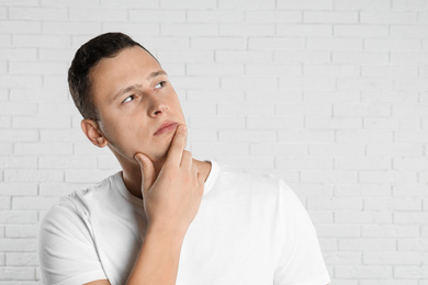 Photo of Handsome young man near white brick wall