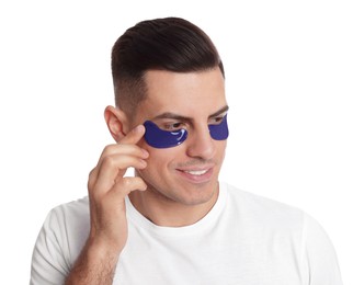 Man applying blue under eye patch on white background