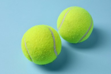 Photo of Two tennis balls on light blue background, closeup