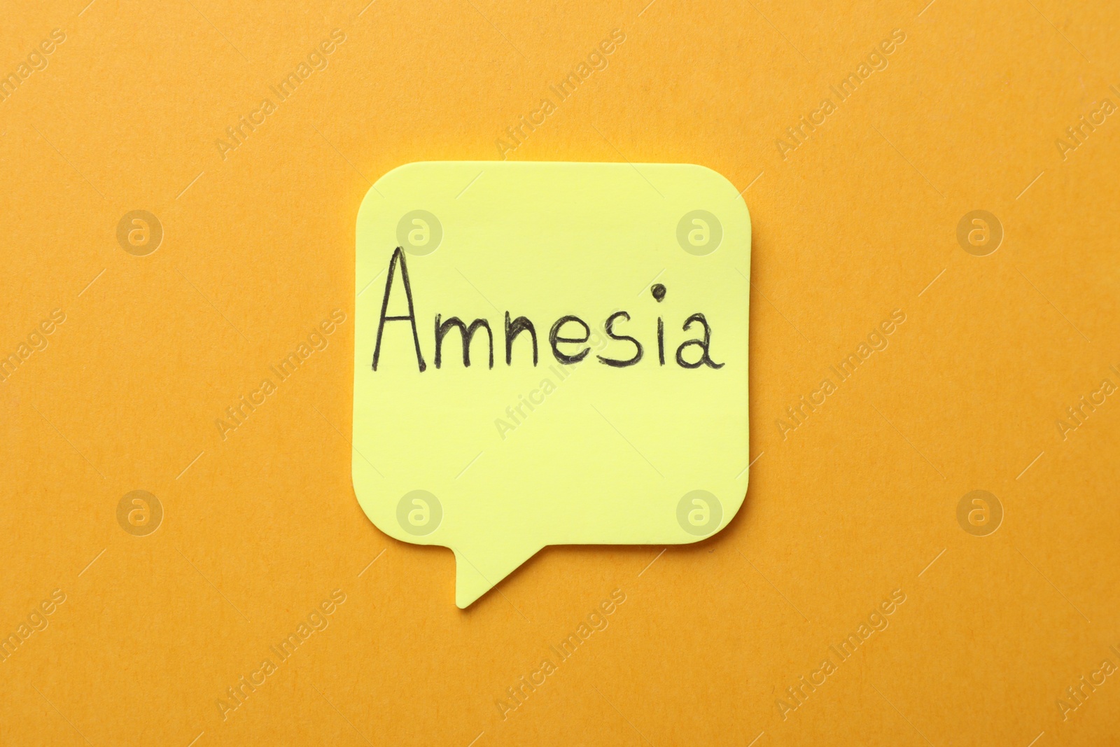 Photo of Yellow sticky note with word Amnesia on orange background, top view