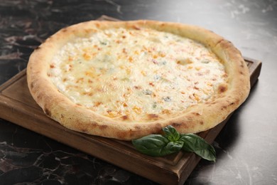 Photo of Delicious cheese pizza and basil on black marble table, closeup