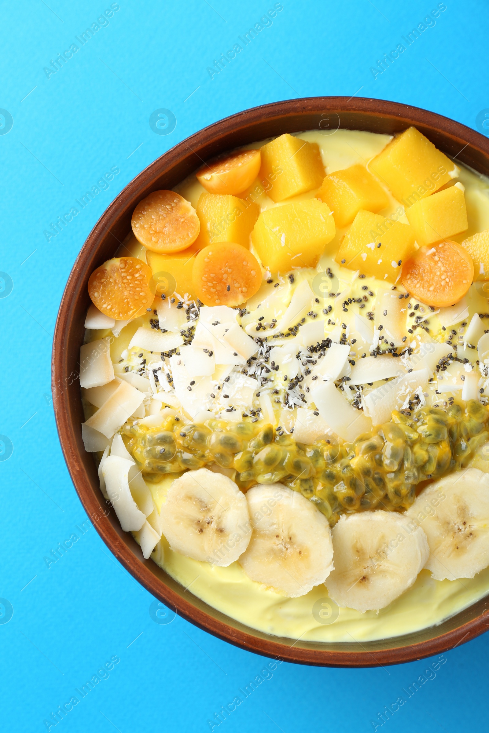 Photo of Tasty smoothie bowl with fresh fruits on light blue background, top view