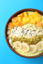 Photo of Tasty smoothie bowl with fresh fruits on light blue background, top view