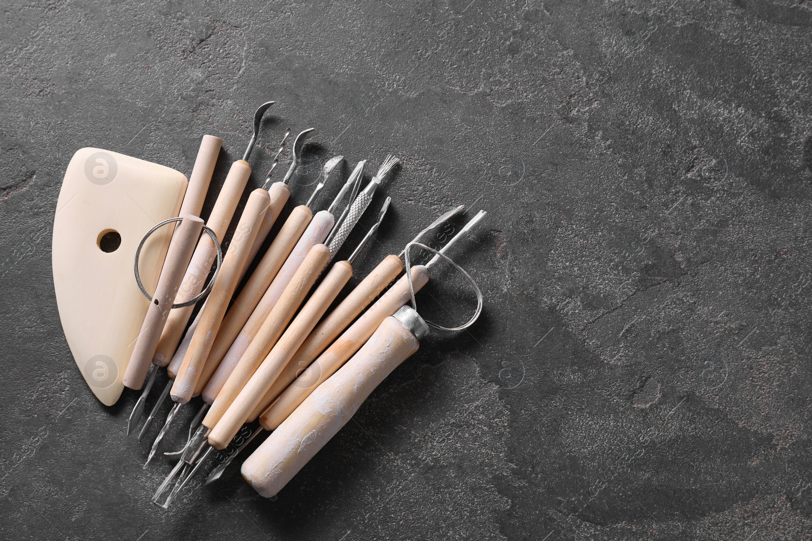 Photo of Set of different clay crafting tools on grey table, top view. Space for text