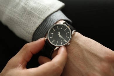 Businessman in jacket with luxury wrist watch on black background, closeup