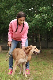 Photo of Female volunteer with homeless dog at animal shelter outdoors