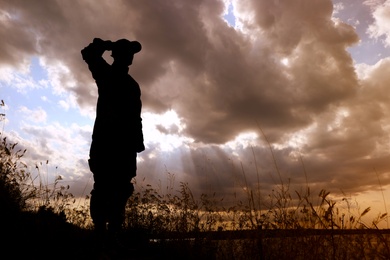 Photo of Soldier in uniform saluting outdoors. Military service