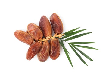Photo of Sweet dates on branch and green leaves against white background, top view. Dried fruit as healthy snack