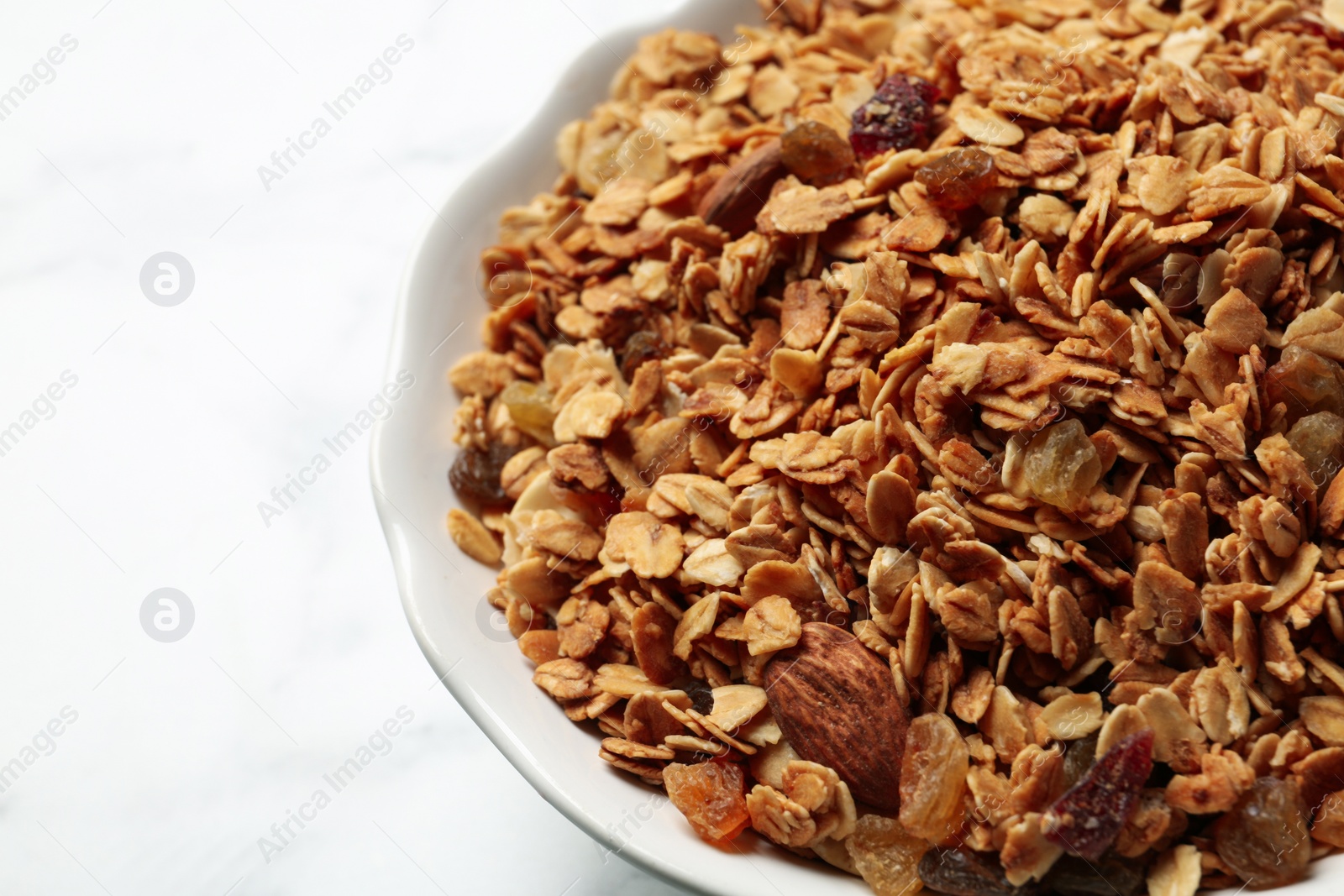 Photo of Tasty muesli with raisins on table, closeup. Healthy breakfast