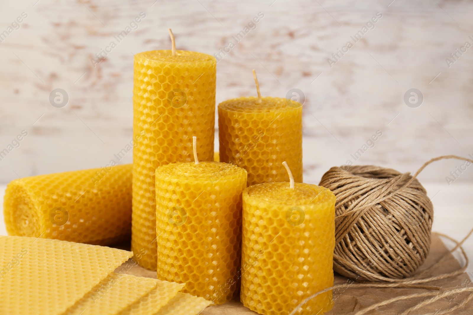 Photo of Stylish elegant beeswax candles, wax sheets and twine on table