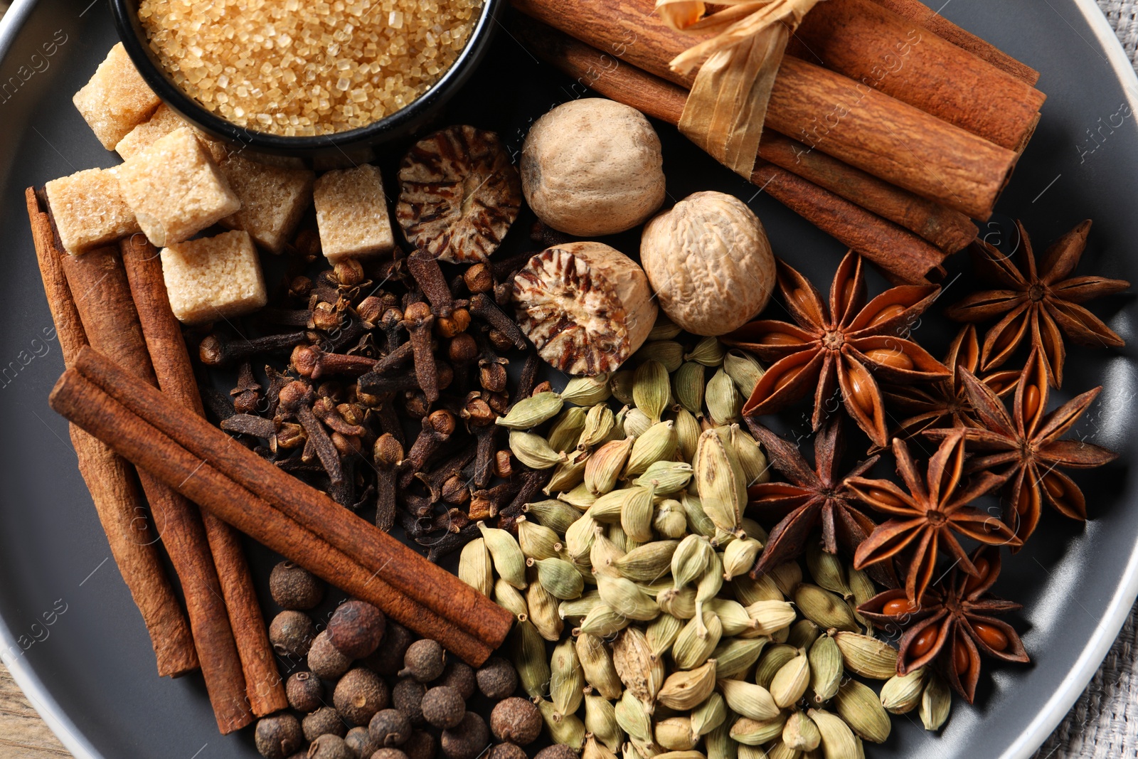 Photo of Different aromatic spices on plate, top view