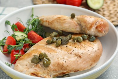 Photo of Delicious cooked chicken fillets with capers and salad on table, closeup