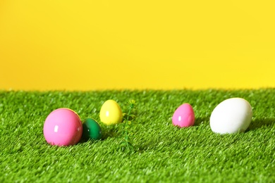 Easter eggs on green lawn against color background, space for text